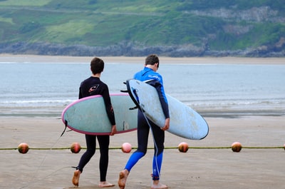 Two men took the surfboard to walk on the beach
